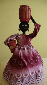 Esta muñeca representa a la mujer de L´Ouest de Camerún que se dirige al campo para recoger sus frutas y verduras que las llevará a su casa en el cesto que lleva en su cabeza. La cesta más pequeña la deja para que su hijo la ayude...